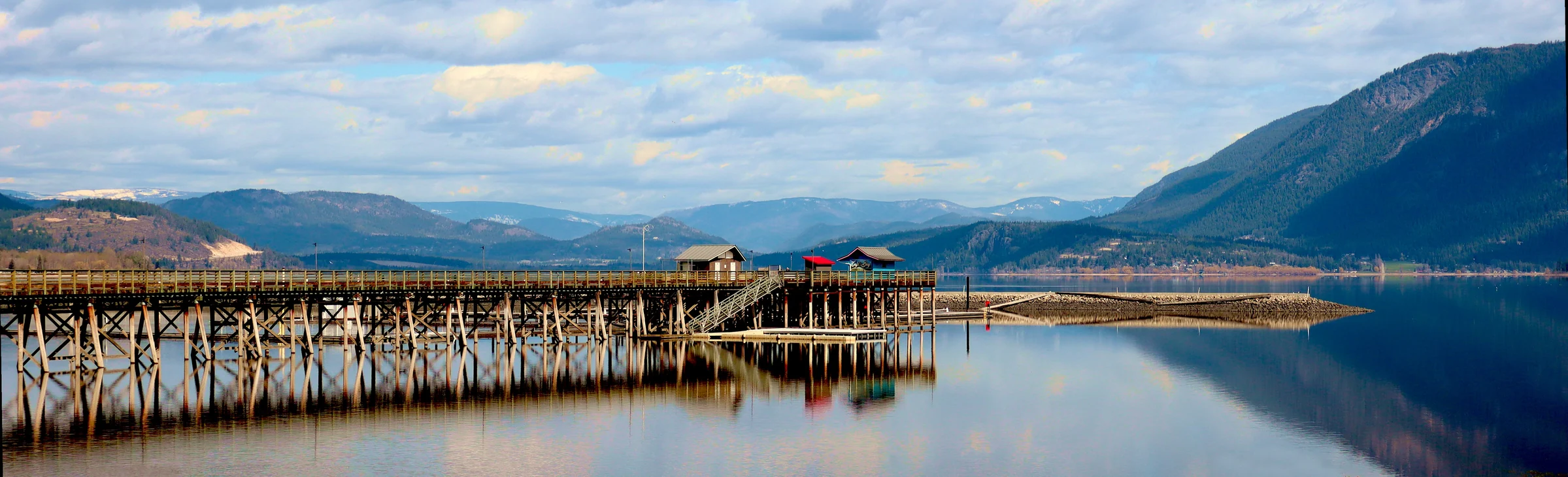 Salmon Arm wharf reflected in Shuswap Lake with the mountains of British Columbia beyond